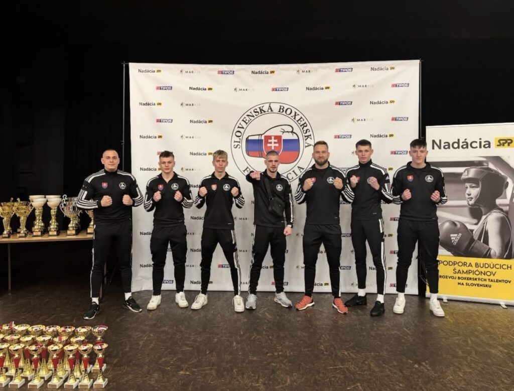 Boxeri v čiernych súpravách pred bannerom Slovenskej boxerskej federácie
