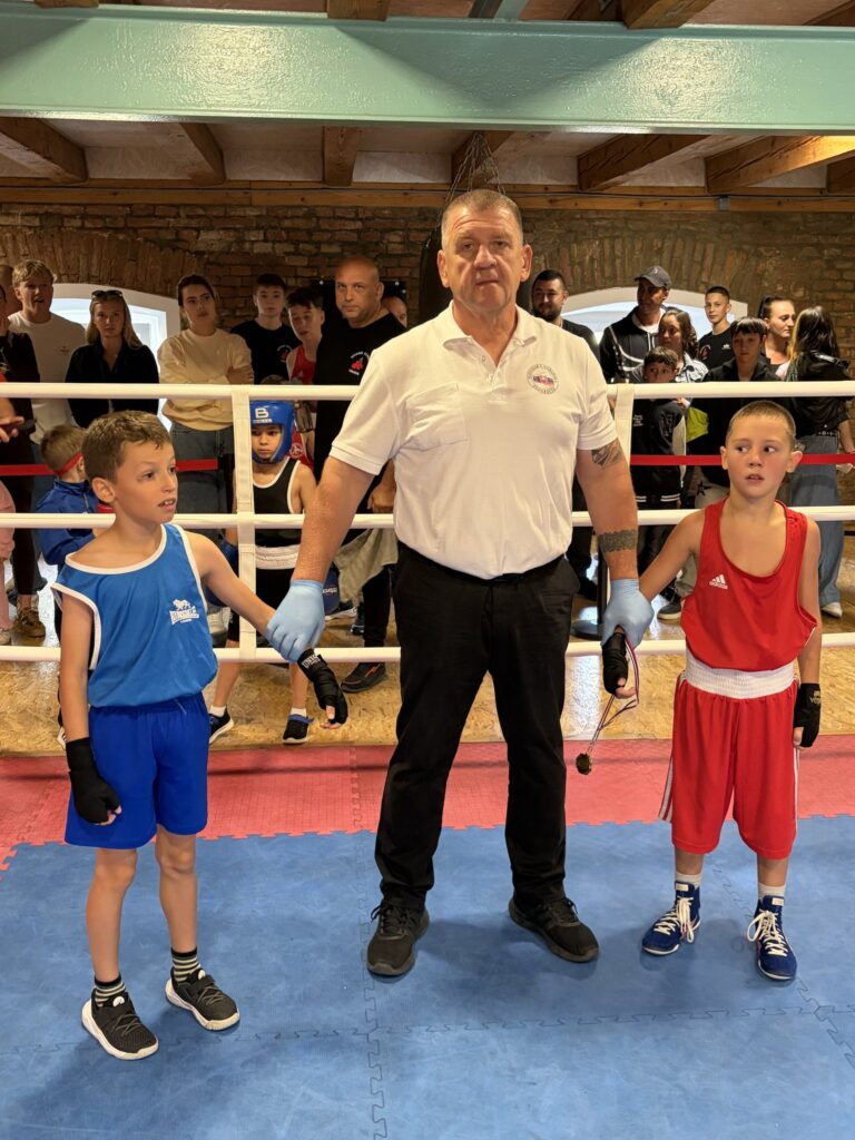 Rozhodca drží za ruky dvoch mladých boxerov po zápase